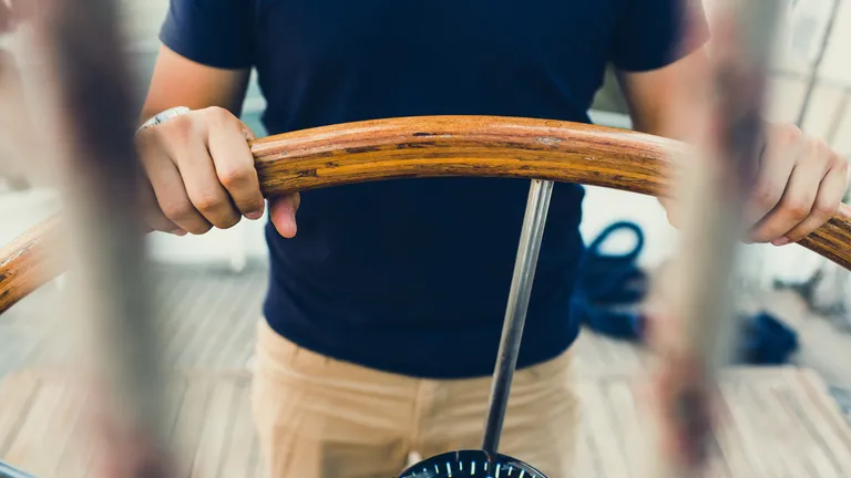 Man holding a ship steering wheel.