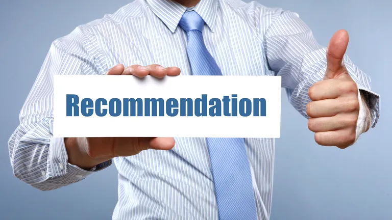Man in formal striped shirt holding sign saying recommendation and does a thumbs up.