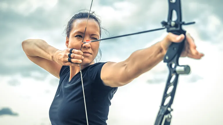 Woman with bow and arrow strung in the bow, she looks in the direction of the arrow.
