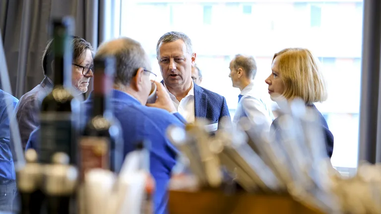 Aperitif at the Keynote Event 2023, three men and one woman stand in a circle and chat.