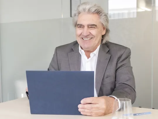 Udo Jäger, an employee of Bosshard & Partner, sits at a table holding a tablet.
