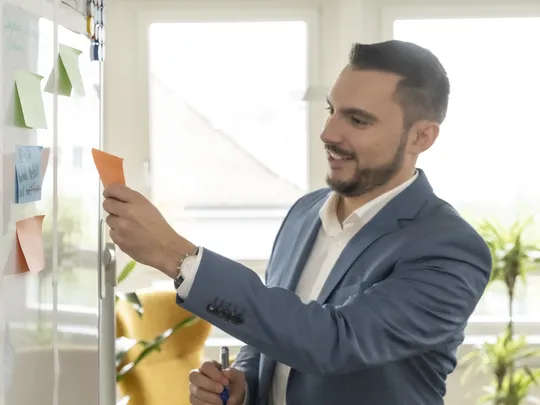 Michael Wirz, a Bosshard & Partner employee stands at the whiteboard holding a pen and a piece of paper.