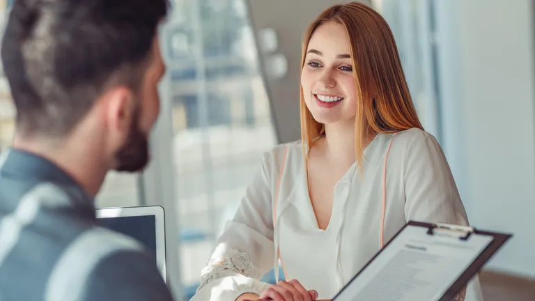 Woman sits opposite a man in a conversation and smiles.