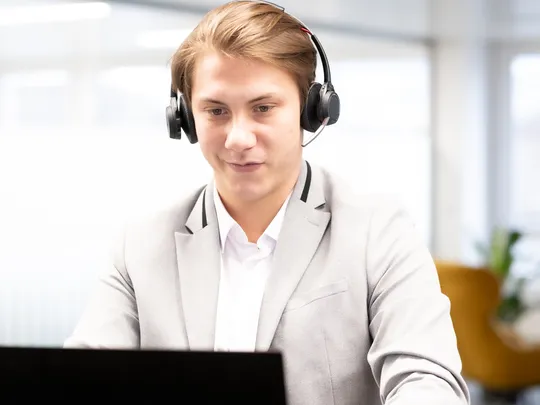 Georg Flügel, an employee of Bosshard & Partner, wears a headset and looks at his laptop.