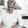 Hanspeter Himmel sits at a desk and writes something on a piece of paper.
