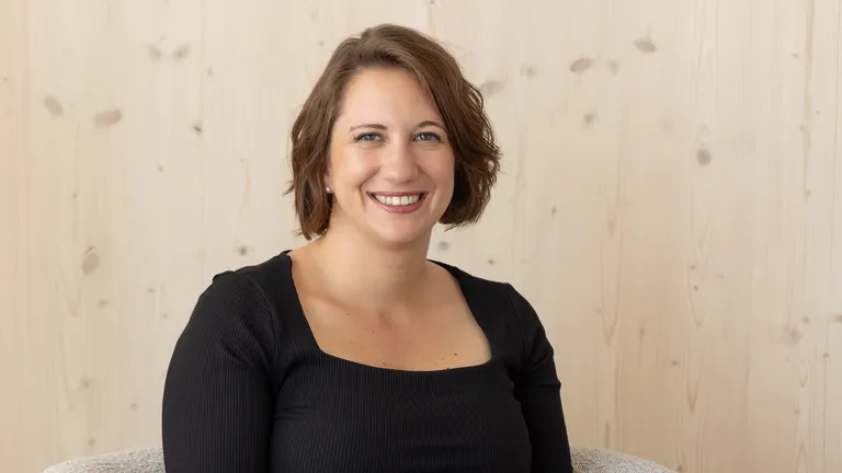 Elise Bourgeois, founder of the onyva agency, smiles into the camera against a light-colored wooden background.