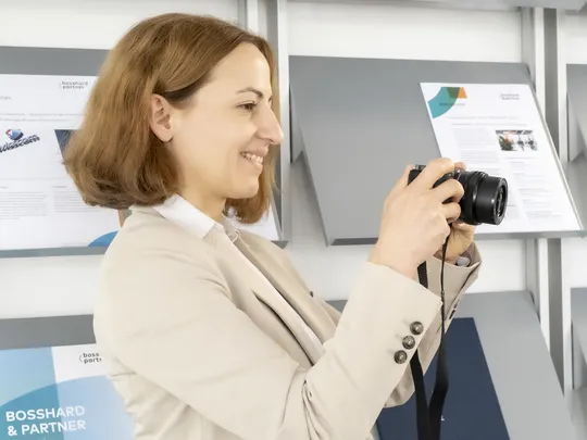Fabienne Geiger, an employee of Bosshard & Partner, holds a camera in her hand and looks at the camera display.