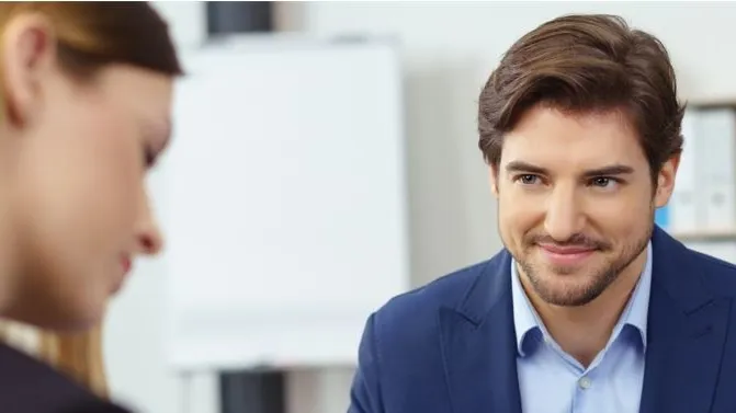 Woman and man in a conversation. The man is wearing a suit and looking at the woman, the woman is looking at something in front of her.