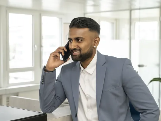 Praveen Rajkumar, an employee of Bosshard & Partner, stands at reception and holds his mobile phone to his ear.
